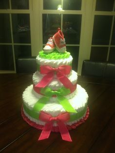 a multi layer diaper cake with pink, green and white ribbons on it's bottom tier