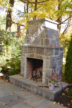 an outdoor fireplace surrounded by trees and leaves