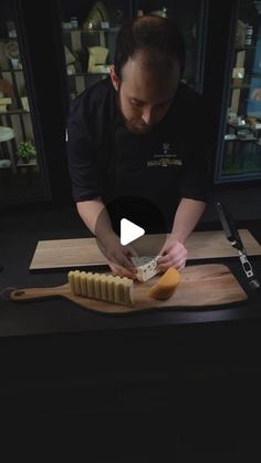 a man cutting cheese on top of a wooden board