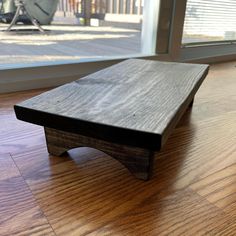 a wooden coffee table sitting on top of a hard wood floor next to a window