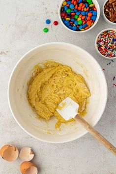 a bowl filled with batter next to bowls of candy