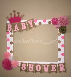 a baby shower photo frame with pink and gold decorations on it's sides, along with tissue pom poms