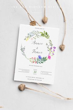 a wedding card with flowers and greenery on it, next to some dried branches