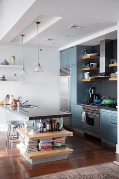 a kitchen with stainless steel appliances and wooden flooring is pictured in this image, there are several books stacked on the counter