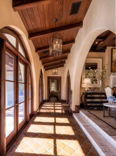 the sun shines through the windows in this hallway leading to another room with large doors