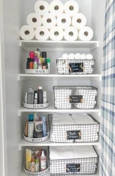 an organized bathroom closet with toilet paper and baskets