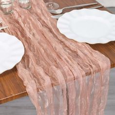 the table is set with white plates and silverware, along with pink organ - dyed napkins