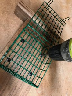 a drill is laying on the floor next to a wire basket with holes in it