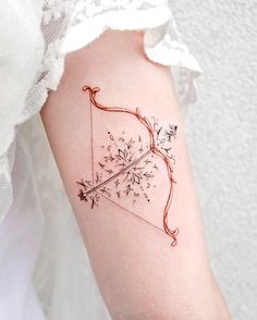 a woman's arm with an arrow and flowers tattoo on the left side of her arm