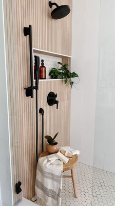 there is a towel on the stool next to the shower head and hand held shower faucet