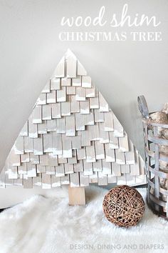 a wooden christmas tree sitting on top of a white rug next to a metal basket