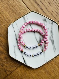 These handmade custom beaded bracelets can be customized with any name or word you'd like! The hot pink floral beads come in 6mm.  Perfect for Mother's Day! You can use words like Mama, Gigi, Nana, Grammy, Gammy, Boy Mom or Girl Mom. The options are endless! These also come in blue (6mm & 8mm), pink (8mm), and red (8mm) floral beads.  These bracelets are made with gold beads that are made from stainless steel, rust and corrosion resistant. The gold beads can be substituted with silver beads. Ple Hot Pink Floral, Word Bracelet, Name Bracelet, Gold Beads, In Hot, Custom Name, Silver Beads, Beaded Bracelet, Pink Floral