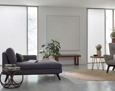 a living room filled with furniture and large windows covered in white blinds on top of them