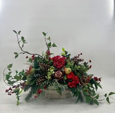 a vase filled with flowers and greenery on top of a table