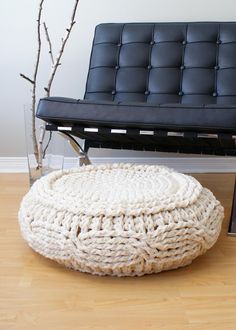 a black couch sitting on top of a hard wood floor next to a white ottoman