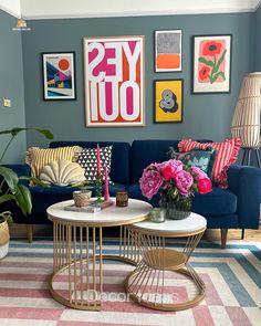 a living room with blue couches and pink flowers on the coffee table in front of it