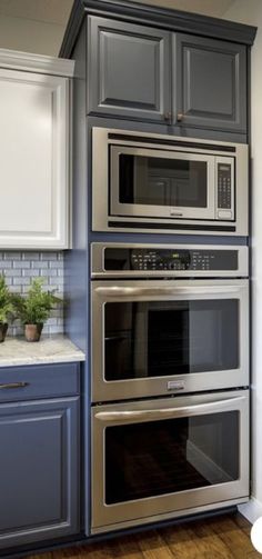 an oven built into the side of a wall in a kitchen with blue cabinets and wood floors