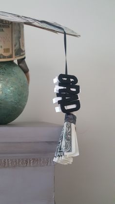 money is hanging from a string on top of a vase with paper notes attached to it