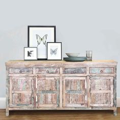 an old dresser with two framed pictures on top and one empty bowl sitting on it