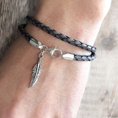 a close up of a person's wrist wearing a bracelet with a feather charm