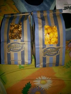 two bags of popcorn sitting on top of a bed