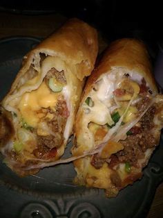 two burritos cut in half sitting on a plate with cheese and other toppings