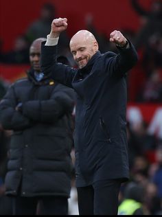 an older man with his fist up on the sidelines during a soccer game,