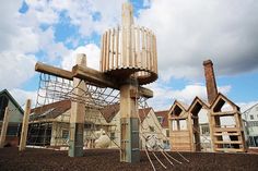 a wooden structure sitting in the middle of a dirt field next to houses and trees