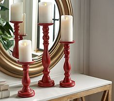 three candles are sitting on a table in front of a mirror with a gold frame