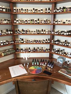 a wooden desk topped with lots of bottles next to shelves filled with different types of items