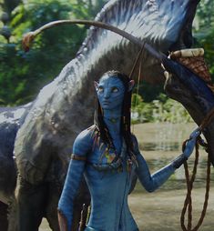 a woman with blue paint on her face and body standing next to an animal