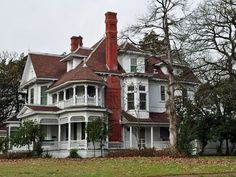 an old victorian style house with white trim and red roof