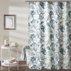 a shower curtain with blue and white floral designs on the outside, in a bathroom