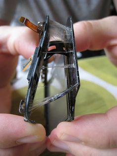 two hands holding an open broken cell phone with the front glass partially taken apart from it