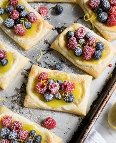 small desserts with fruit on them are sitting on a baking sheet and ready to be eaten