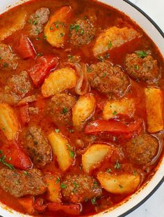 a bowl filled with meat and vegetables in a tomato based stew, garnished with parsley