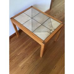 a table with a glass top and wooden legs on the floor next to a mirror