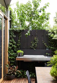 an outdoor kitchen and dining area with wooden decking, potted plants and table