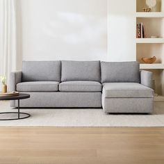 a living room with a gray couch and coffee table in front of a white wall