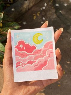 a person holding up a card with clouds and a moon in the sky on it