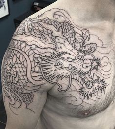 a man's chest with a dragon tattoo on his left arm and chest is covered in black ink