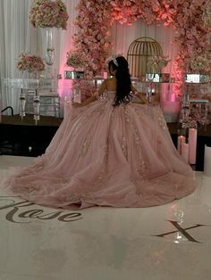 a woman in a pink ball gown sitting on the floor next to flowers and candles