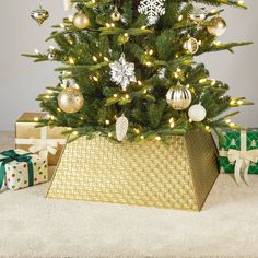 a small christmas tree with gold and silver ornaments in a golden basket next to presents