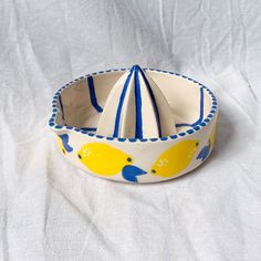 a yellow and blue bowl sitting on top of a white tablecloth covered floor next to a paper cone