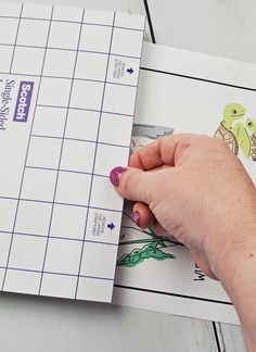 a person's hand holding a piece of paper next to a crossword puzzle