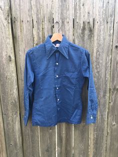 This is a great 70's button up that is stained up and looks amazing. If you want something that is well worn and is super comfortable, get this beauty in your life now. Measurements: Pit to pit: 16 1/2 inches Collar to bottom front: 20 inches Collar to bottom back: 23 inches Sleeve Length (from collar): 25 1/2 inches Shoulder to shoulder: 14 1/2 inches Size on tag: no tag size (measures like women's Small/XS) Vintage Fitted Pre-washed Tops, Fitted Vintage Pre-washed Tops, Blue Pre-washed Long Sleeve Shirt, Blue Long Sleeve Pre-washed Shirt, Vintage Pre-washed Fall Shirt, Vintage Long Sleeve Shirt With Button Cuffs, 1970s Long Sleeve Cotton Shirt, 1970s Style Long Sleeve Cotton Shirt, Vintage Blue Shirt For Fall