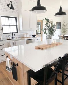 a large kitchen with white counters and black chairs around the countertop, along with an island in the middle