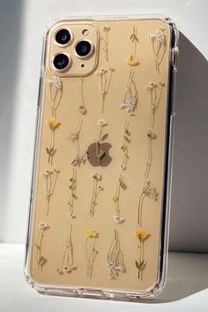 an iphone case with flowers on it sitting on top of a white table next to a wall