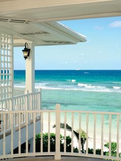 a porch with a light on it next to the beach and ocean in the background