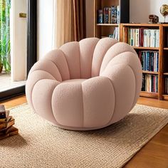 a pink chair sitting on top of a wooden floor next to a book shelf filled with books